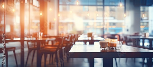 A restaurant with wooden tables and chairs in a city building, featuring blurry windows and glass fixtures. The room has a cozy atmosphere perfect for events © 2rogan