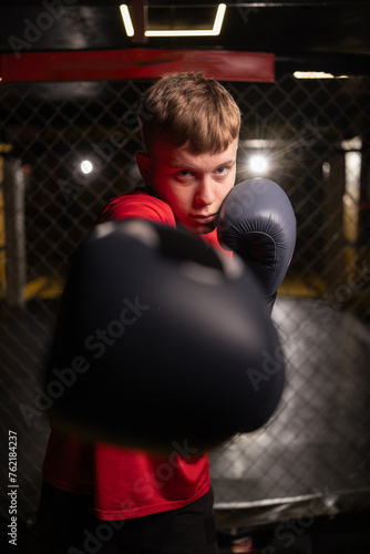Portrait of young man with boxing gloves in gym, close-up.