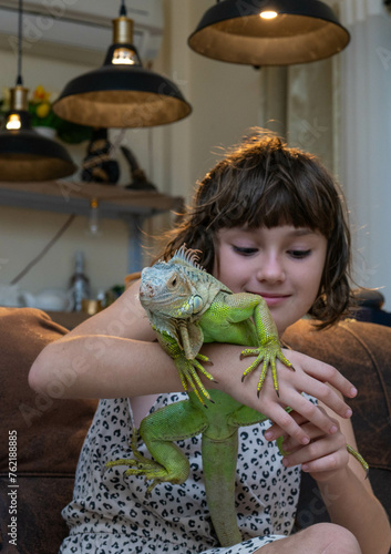 Reptile in human hands. The girl smiles and holds an iguana in her hands (ID: 762188885)