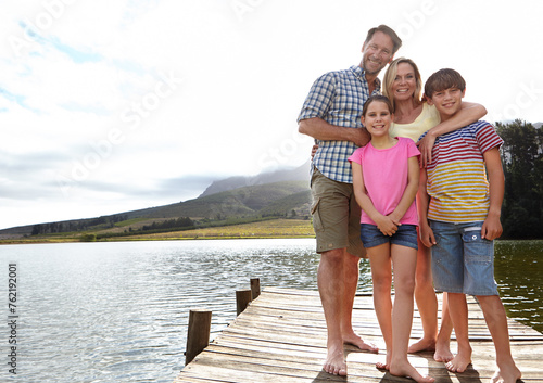 Family, portrait by lake and outdoor on pier for travel with vacation, parents and kids with fresh air in nature for bonding. Love, support and trust, happy people and adventure together with smile