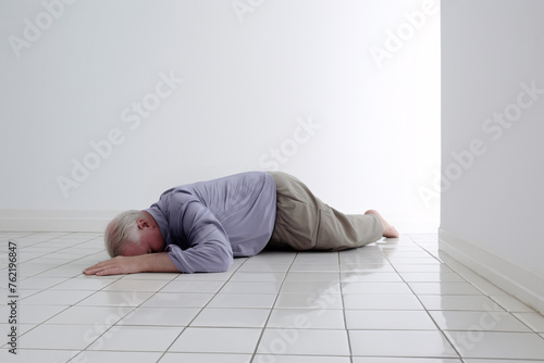 An old man accidentally slipped and fell face down and passed out in a bathroom with slippery floor tiles. Copy space.