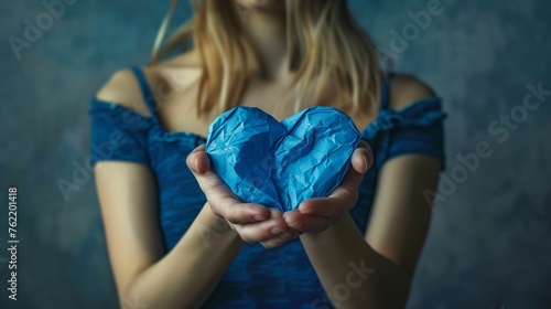 Frau hÃ¤lt ein blaues Papierherz in den HÃ¤nden photo