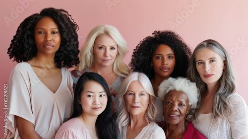 Group of diverse women of different ages and ethnities posing together, symbolizing unity and multigenerational beauty on a pink background. © midart
