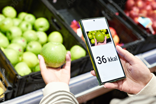 Checking calories on an apple fruit in store with smartphone