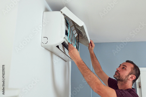 Man cleaning and maintaining air condition unit. photo