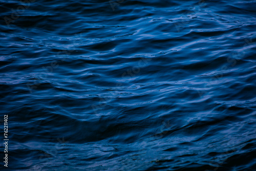 Blue ocean water with waves background. An abstract background of seawater flow under light exposure.