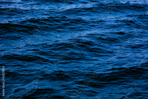Blue ocean water with waves background. An abstract background of seawater flow under light exposure.