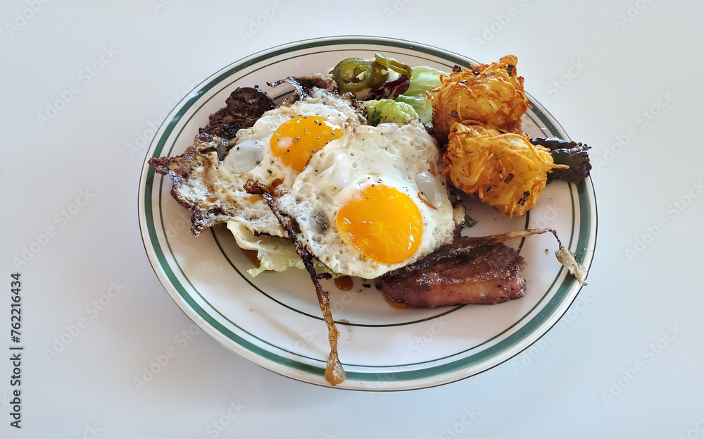 morning breakfast meal with fried eggs, sunny-side-up, hashbrowns, crispy, sizzling, skillet bacon on a white plate isolated on a white background morning breakfast meal with fried eggs, sunny-side-up, hashbrowns, crispy, sizzling, skillet bacon on a white plate isolated on a white background