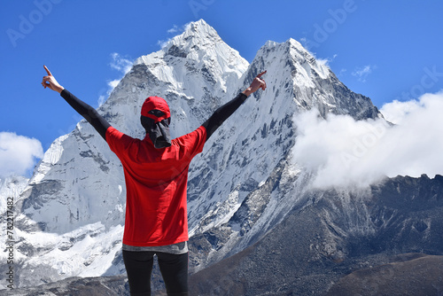 Female hiker with open arms on top of mountain. Happy woman enjoying the view of Mount Ama Dablam in Himalaya, Nepal