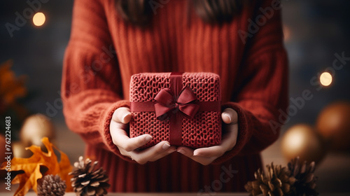 Red gift box in woman hands on autumn background