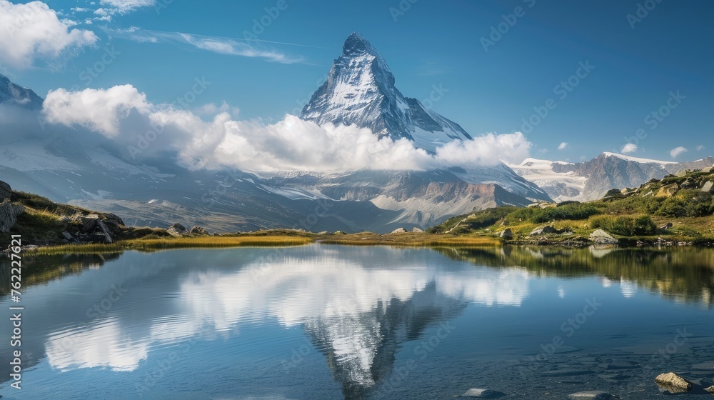 A pristine mountain peak, towering into the sky and surrounded by fluffy white clouds, with a clear alpine lake below.