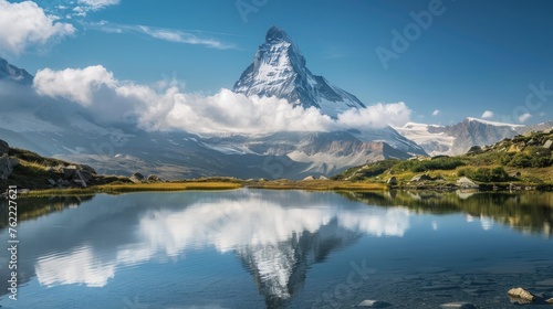 A pristine mountain peak  towering into the sky and surrounded by fluffy white clouds  with a clear alpine lake below.