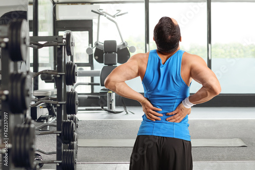 Man at a gym holding his stiff spine