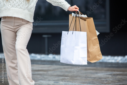 Cropped image of young woman holding shopping bags while walking in city