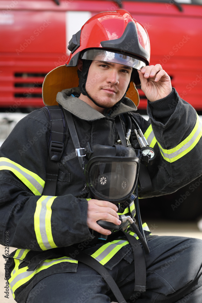 Portrait of fireman wearing fire fighter turnouts and red helmet, hand on visor Portrait of fireman wearing fire fighter turnouts and red helmet, hand on visor
