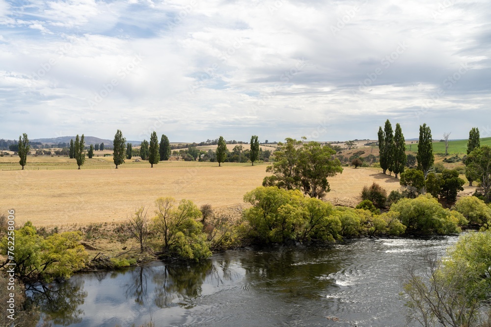 flowing river past farmland in summer, in the Tasmania wilderness. Lake with a Sandy beach and trees in Australia flowing river past farmland in summer, in the Tasmania wilderness. Lake with a Sandy beach and trees in Australia