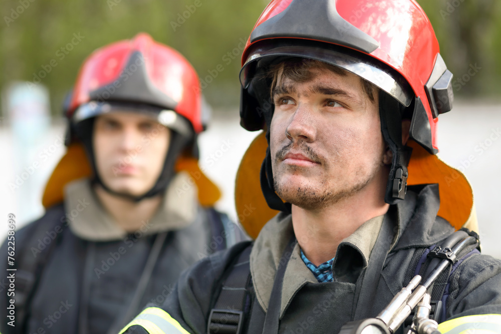 Portrait of two heroic fireman in protective suit and red helmet, closeup Portrait of two heroic fireman in protective suit and red helmet, closeup