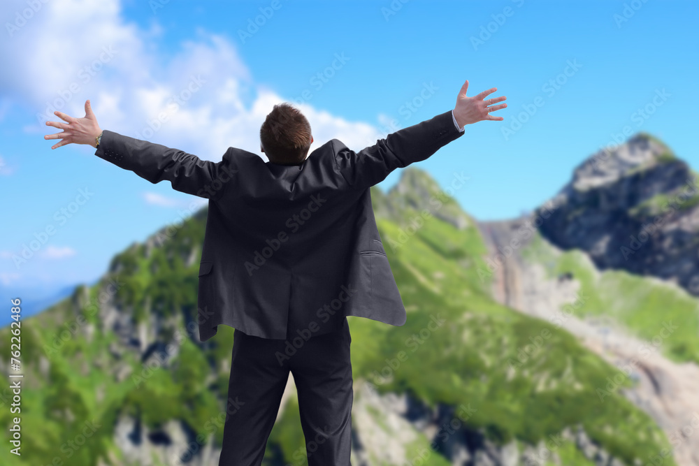 Collage with barefooted man in suit stands back and open hands against background of mountains Collage with barefooted man in suit stands back and open hands against background of mountains