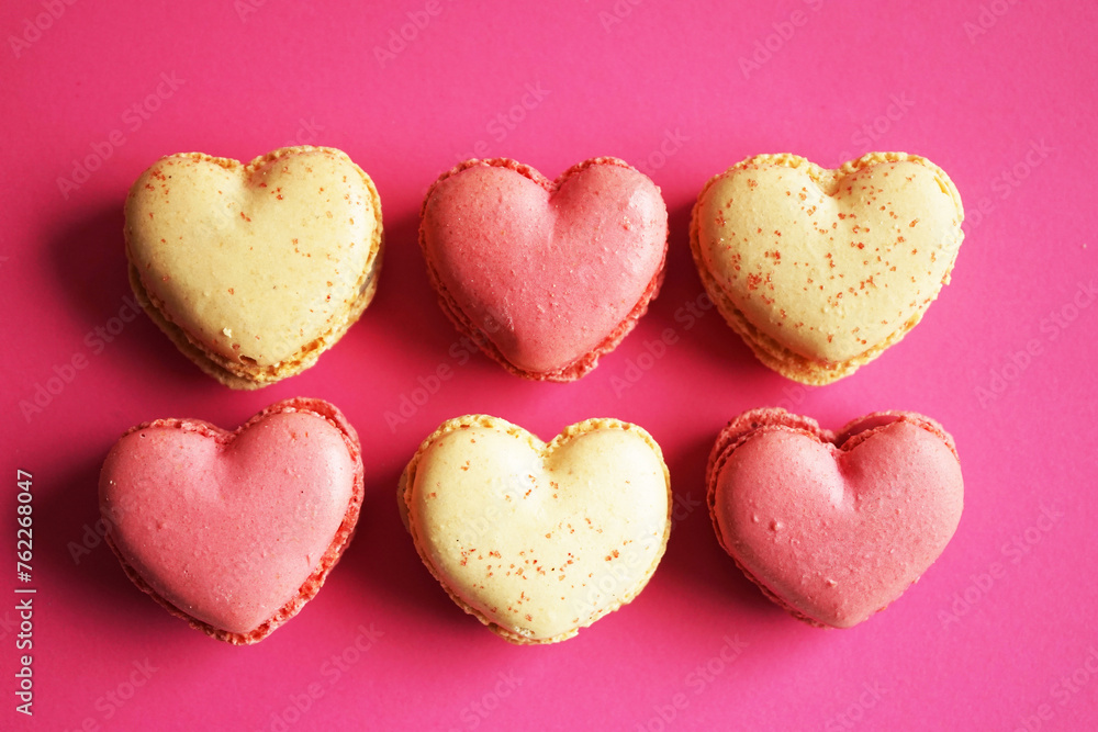 Macarons in the shape of hearts on a pink and yellow background Macarons in the shape of hearts on a pink and yellow background