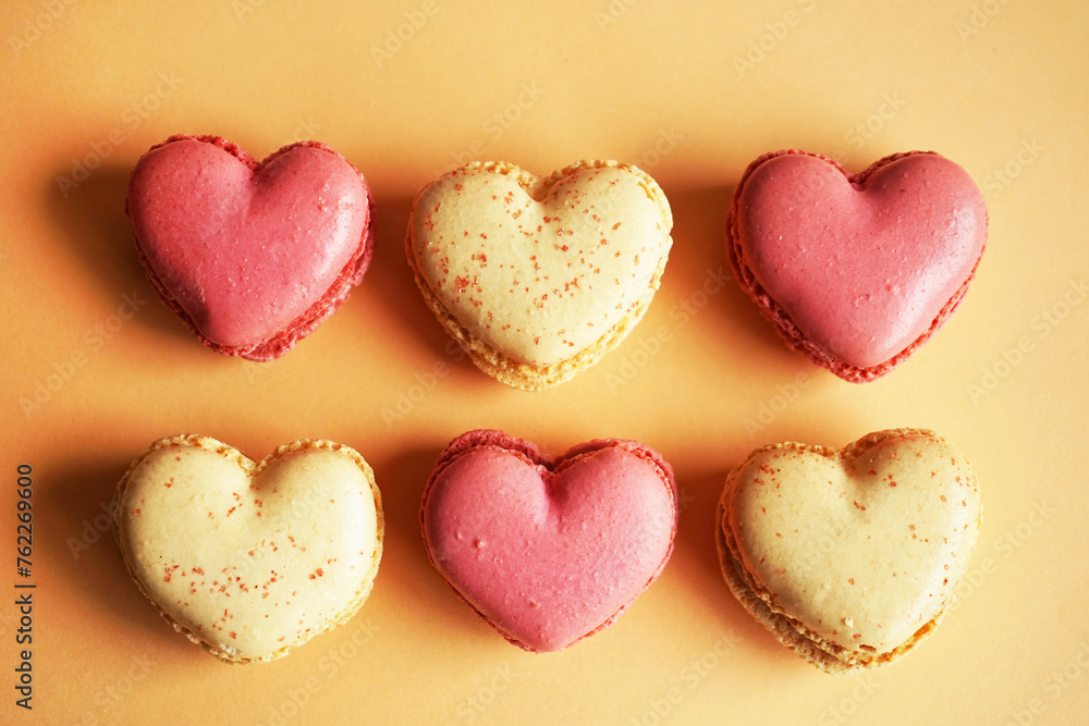Obraz premium Macarons in the shape of hearts on a pink and yellow background