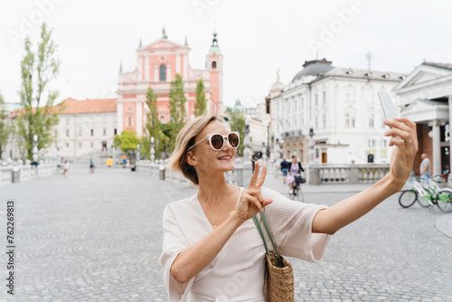 Happy female using smart phone on the Triple bridge in Ljubljana, Slovenia, Europe. photo