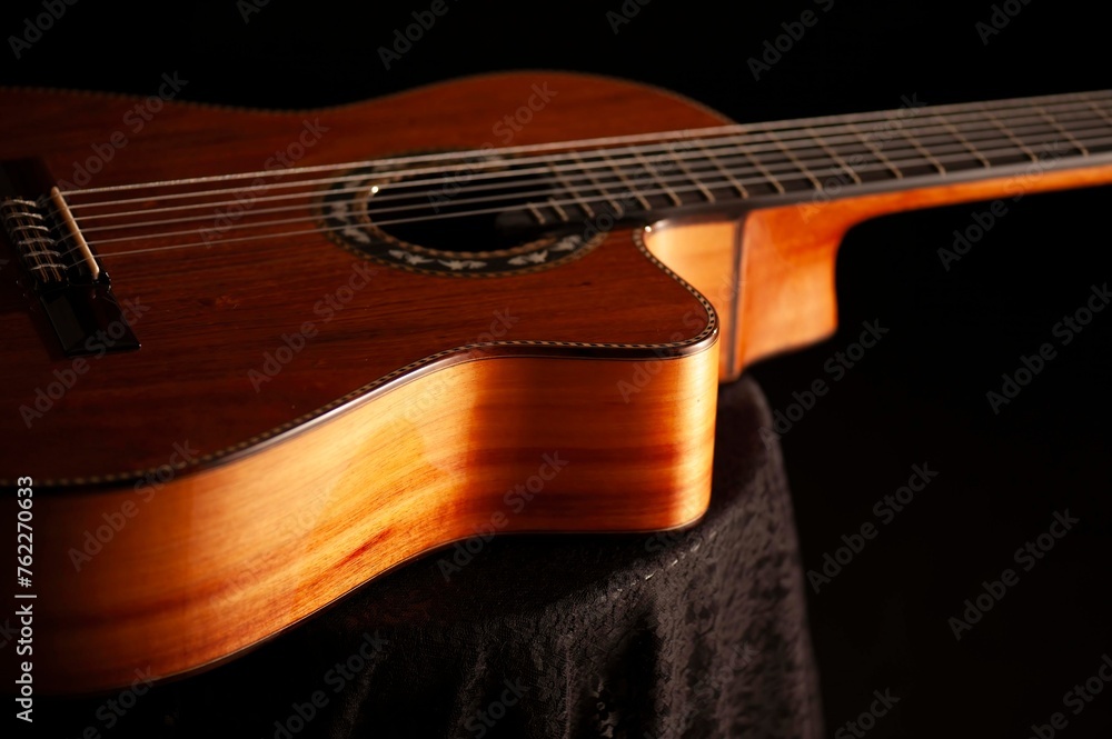 Obraz premium Classical Spanish flamenco guitar close up, dramatically lit isolated on black background with copy space.