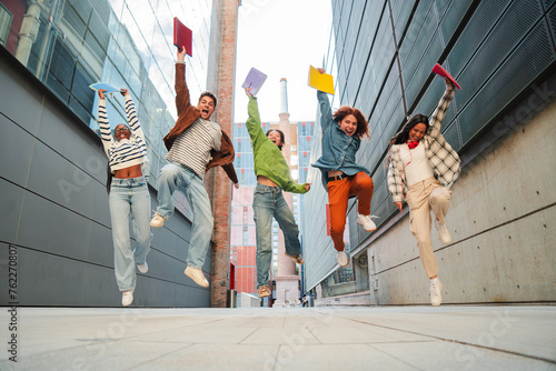 Εκτύπωση καμβά Group of real teenage students having fun jumping up at university campus