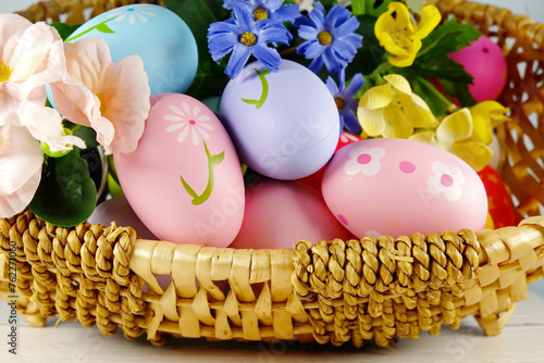 Easter Eggs in the basket with bakery cake fresh baked on white wooden table background