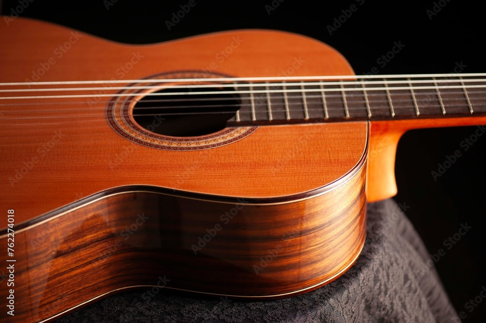 Obraz premium Classical Spanish flamenco guitar close up, dramatically lit isolated on black background with copy space.