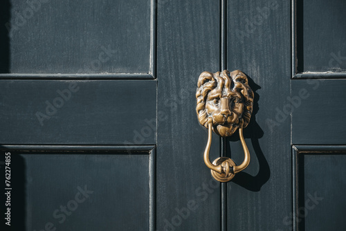 Close up of a lion's head door knocker on a black door. photo