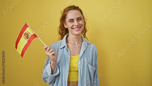 Cheerful woman holding spanish flag against yellow background expresses patriotism and positivity. photo