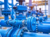 Close-up of blue industrial pipeline valves with blurred background highlighting complexity and infrastructure.
