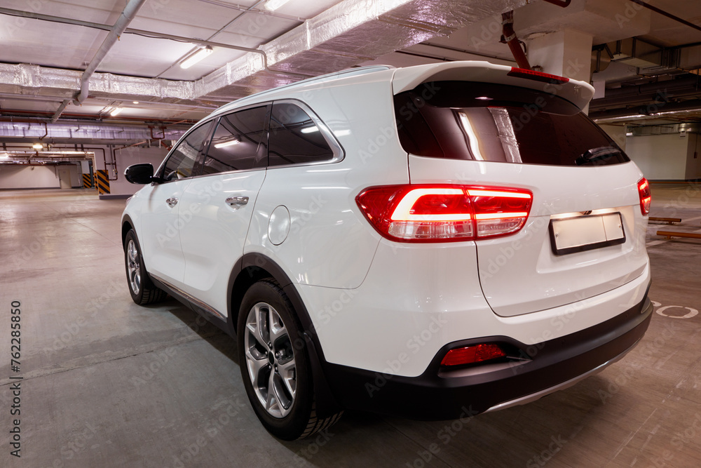 White car with tail lights on at underground parking, rear view. White car with tail lights on at underground parking, rear view.