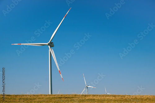 Wind turbines in the field against a blue sky in summer.
