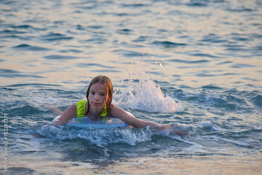 A smiling, happy teenage girl is swimming in the sea or pool on an inflatable ring.