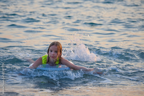 A smiling, happy teenage girl is swimming in the sea or pool on an inflatable ring.