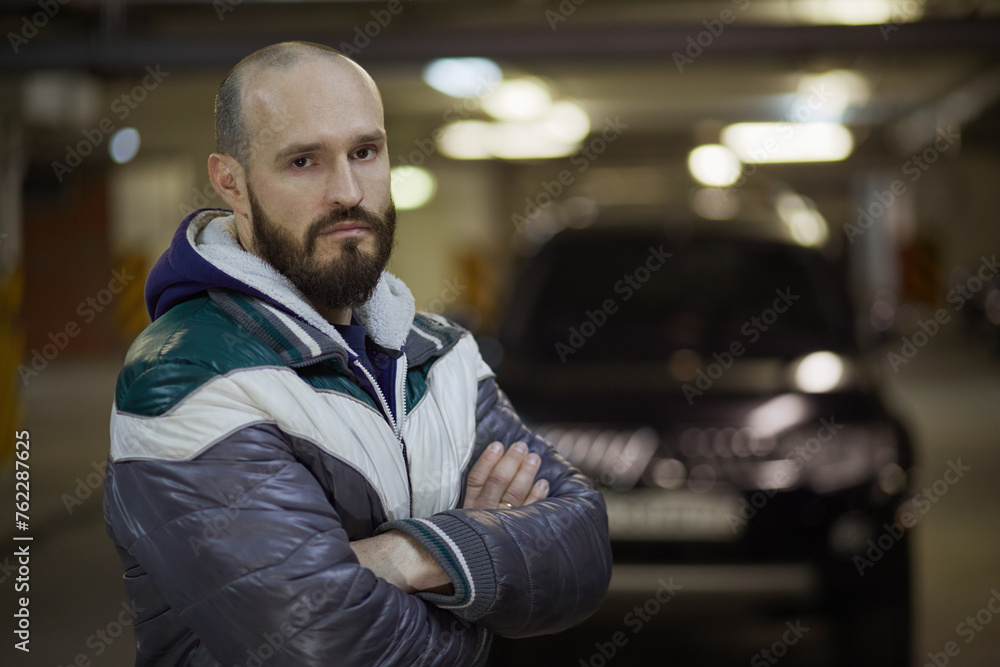 Half-length portrait of bearded man standing with arms folded on chest at underground parking. Half-length portrait of bearded man standing with arms folded on chest at underground parking.