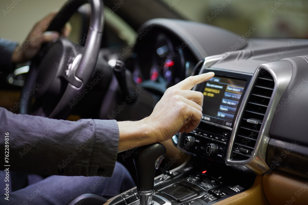 Man operates navigator in modern car at underground parking. Man operates navigator in modern car at underground parking.