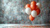 Orange and white balloons and confetti on a background on a concrete gray wall.