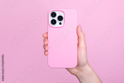 iPhone 15 Pro in female hand in pink silicone cover isolated on pink background phone case mock up in monochrome colours back view