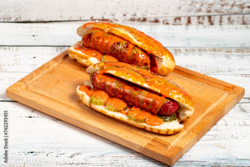 Hot dog with ketchup and yellow mustard on wood background