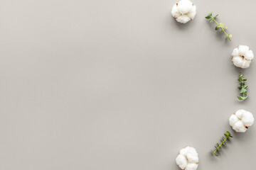 Flowers border with green eucalyptus branches and dry cotton flowers on grey background top view copy space
