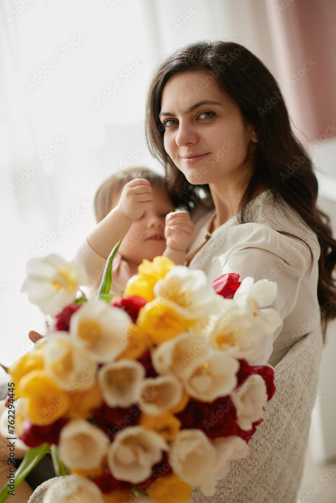 Cute little baby daughter and mom with flowers tulips. Mother and child hugging. Happy mother's day. Cute little baby daughter and mom with flowers tulips. Mother and child hugging. Happy mother's day.