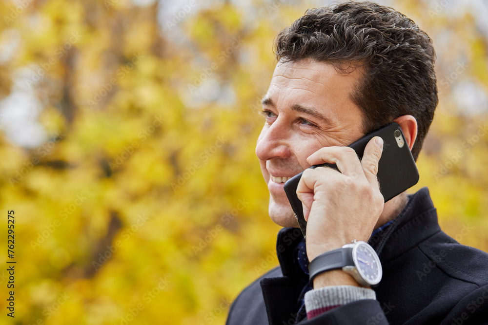 Smiling middleaged man talking cell phone outdoor in park. Smiling middleaged man talking cell phone outdoor in park.