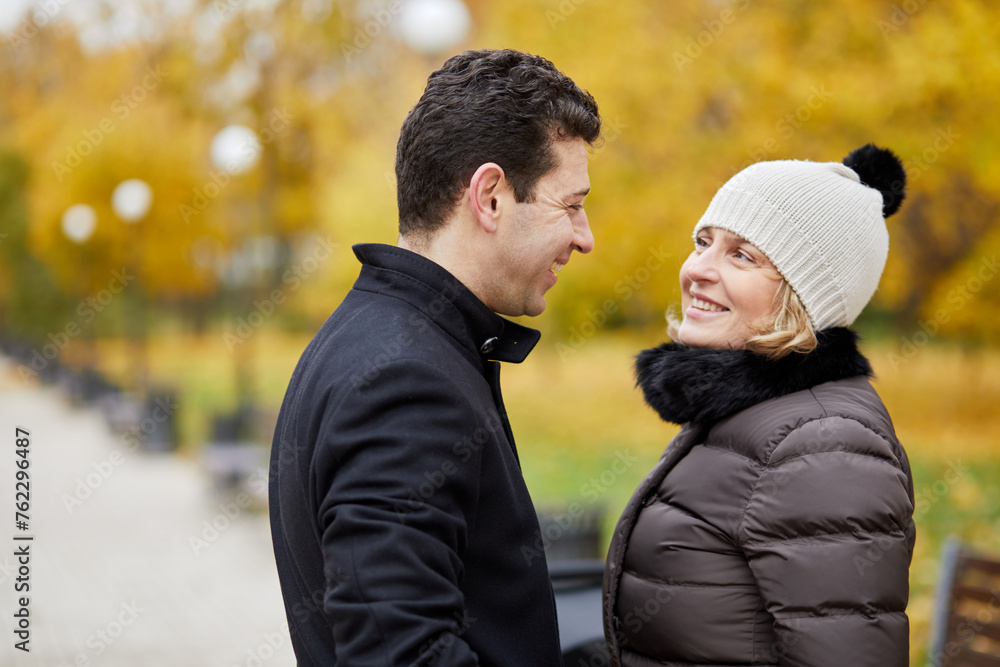 Fototapeta premium Half-length portrait of smiling man and woman in autumn park, profile view.