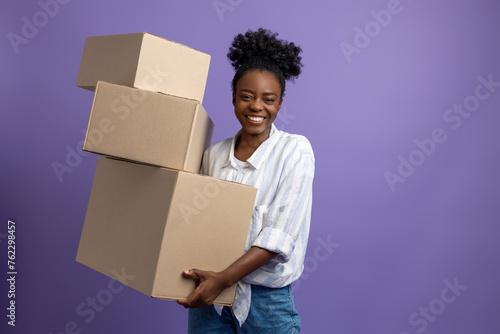 Dark-skinned young woman with boxes in hands looking contented