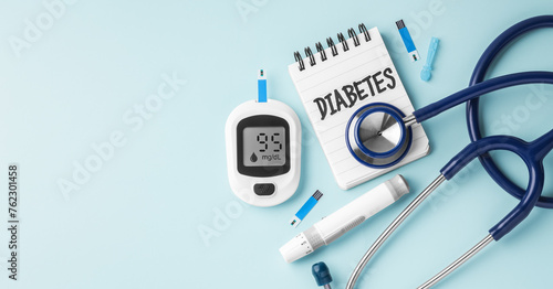Diabetes concept with blood sugar meter and stethoscope on light blue background, top view