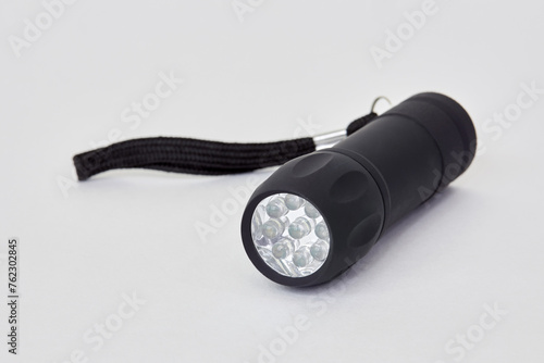 Black poket LED flashlight on white background. photo