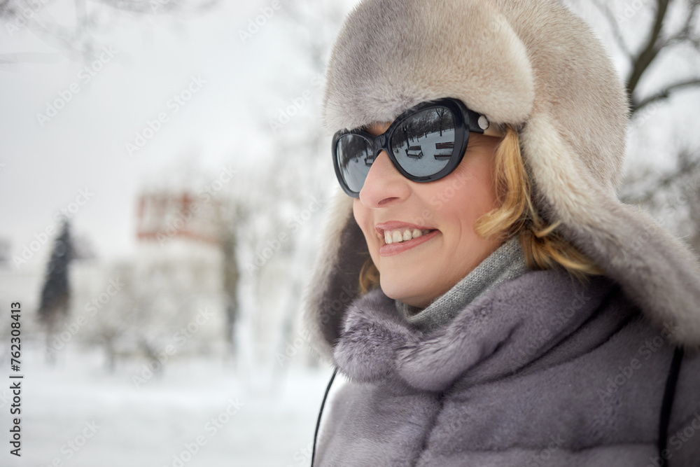 Close-up face of smiling woman in dark sunglasses in winter park. Close-up face of smiling woman in dark sunglasses in winter park.