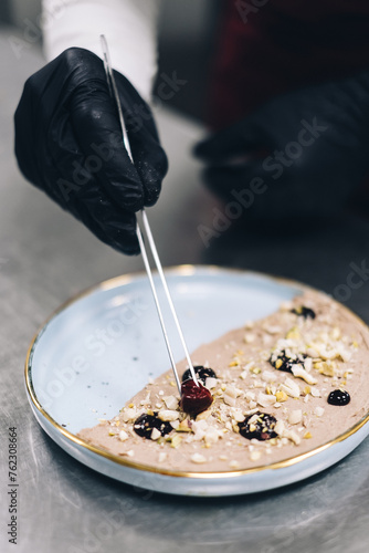 The chef prepares the dish. Chef's hand in the frame. Cook on a light background. Cooking. Sprinkles spices on food